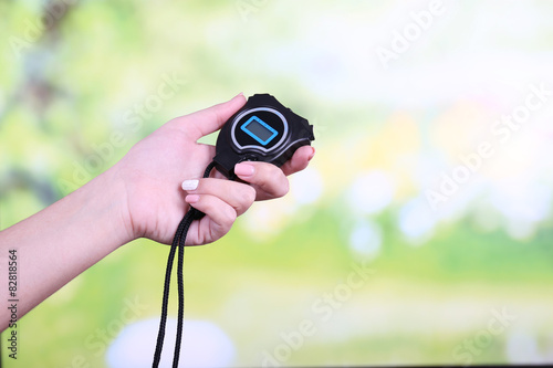 Electronic sport timer in  female hand on bright blurred background photo