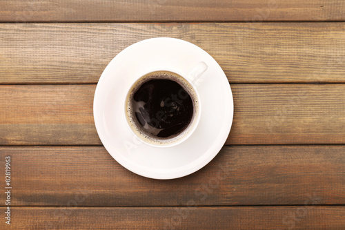 Cup of coffee on wooden table, top view