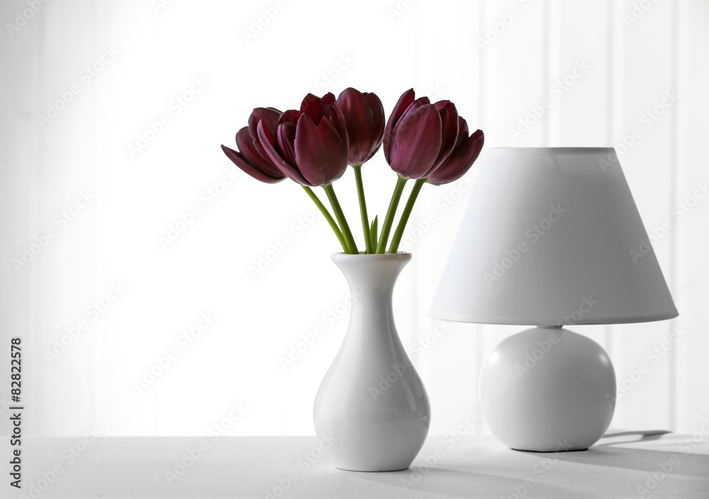 Beautiful violet tulip in vase with lamp on light background Beautiful violet tulip in vase with lamp on light background