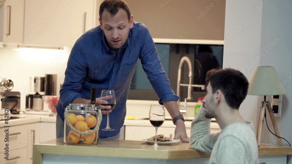 Two male friends talking and drinking wine in the kitchen
Two male friends talking and drinking wine in the kitchen