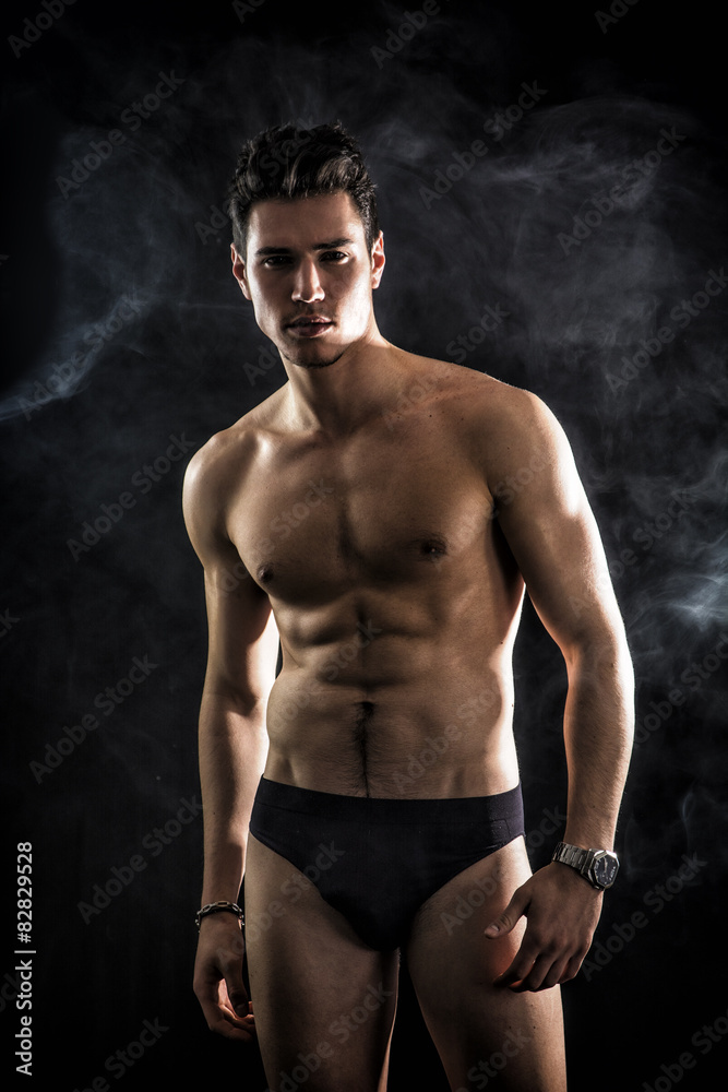 Handsome, fit young man wearing only underwear standing on black Handsome, fit young man wearing only underwear standing on black
