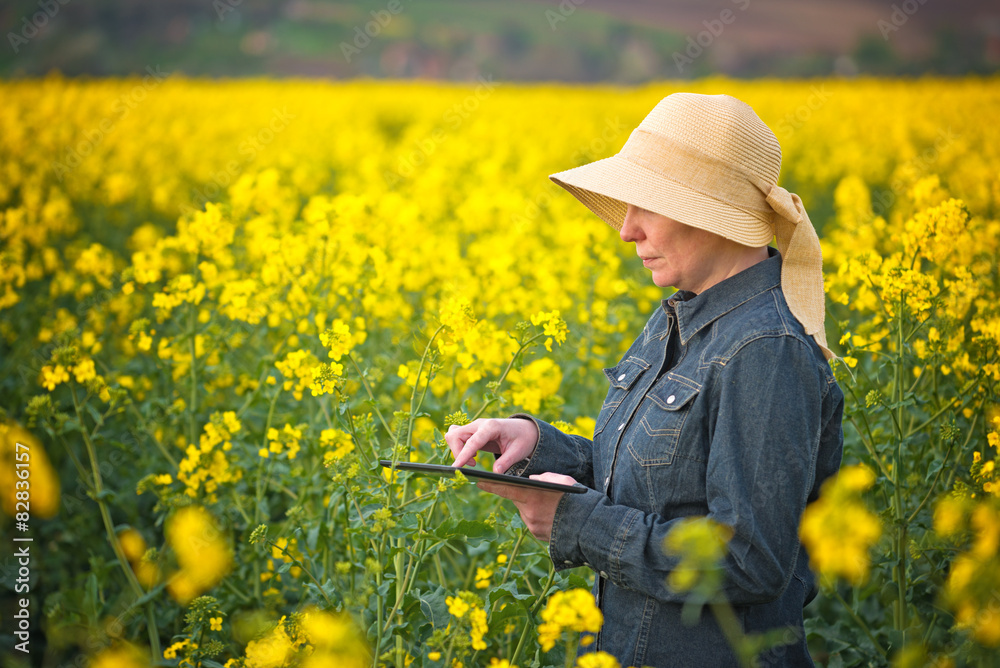 Fototapeta premium Female Farmer with Digital Tablet in Oilseed Rapeseed Cultivated
