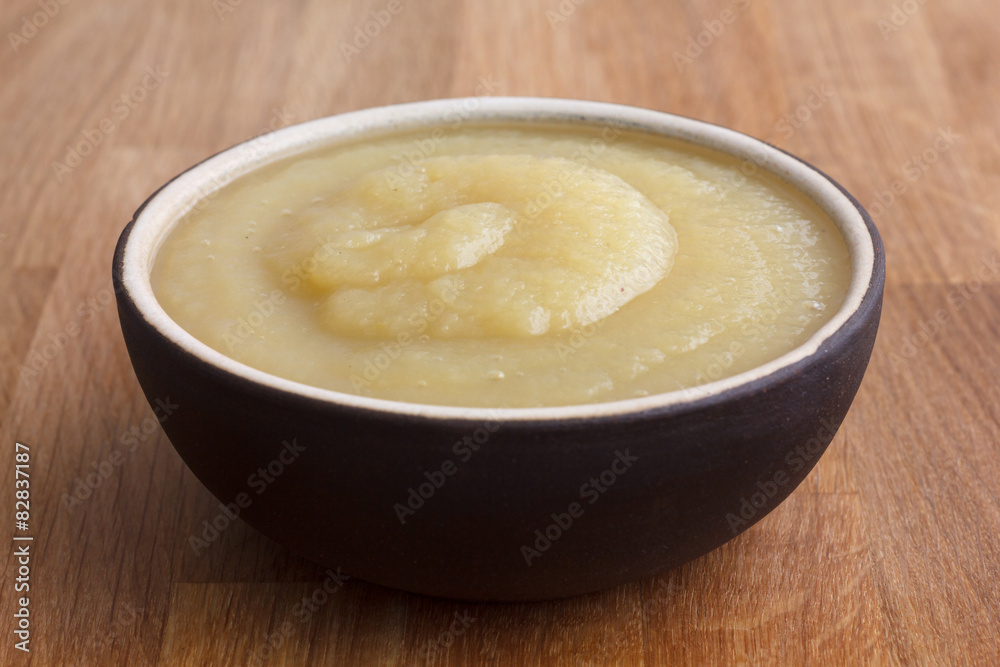 Apple sauce in rustic brown dish on dark wood. Apple sauce in rustic brown dish on dark wood.