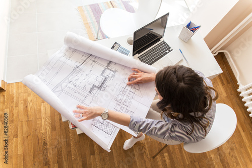 Female architect working at home.She looking at blueprint. photo