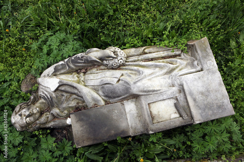 Fallen angel. Destroyed tombstone at the abandoned cemetery. photo