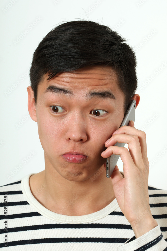 Astonished young Asian man using a smartphone Astonished young Asian man using a smartphone