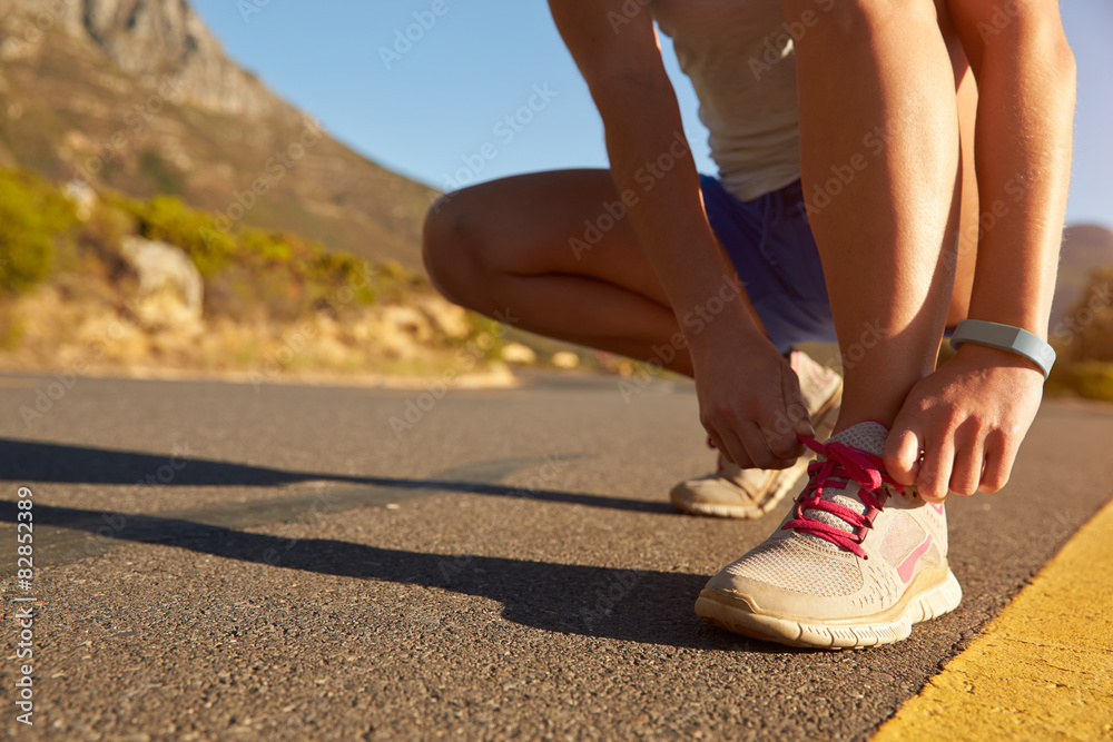 Cropped shot of female jogger doing up her shoe lace