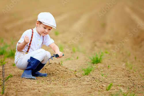 cute little farmer working with spud on spring field