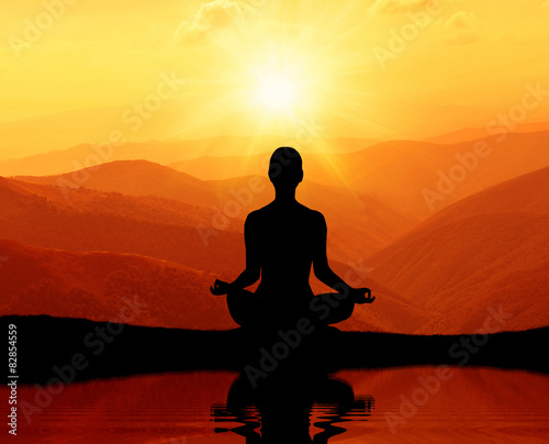   Man meditating in yoga position on the top of mountains