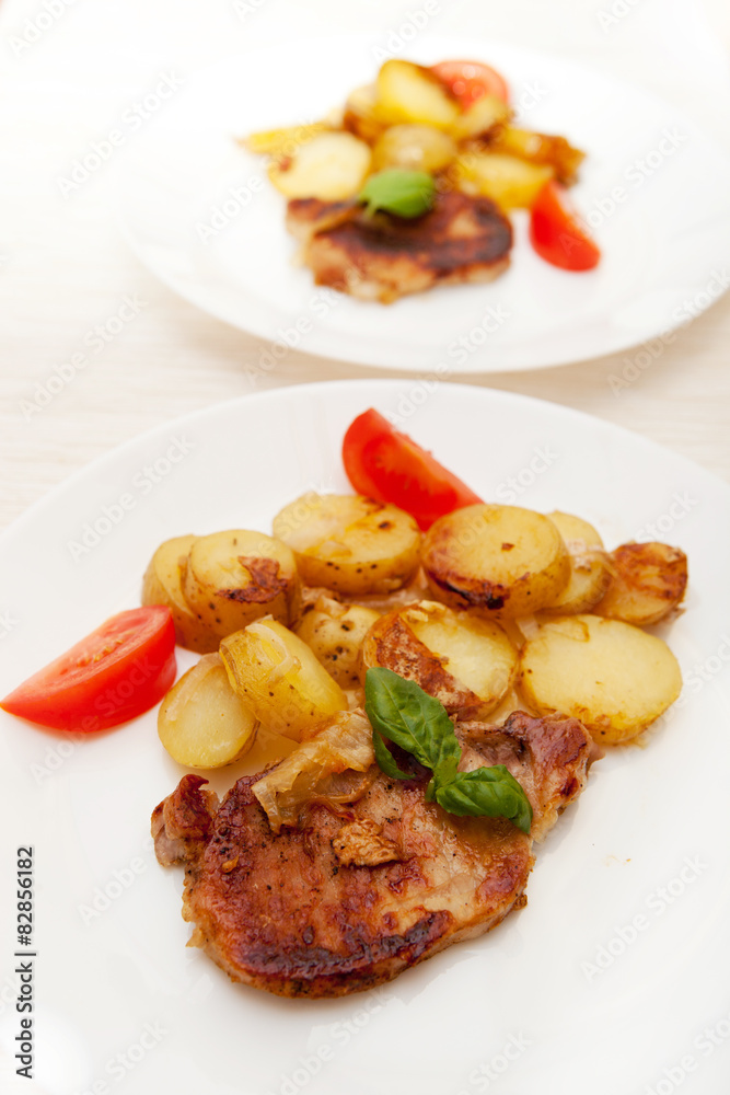 Grilled pork steak swith grilled potato and fresh tomato 