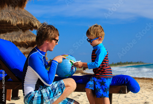 father and son playing with globe on the beach