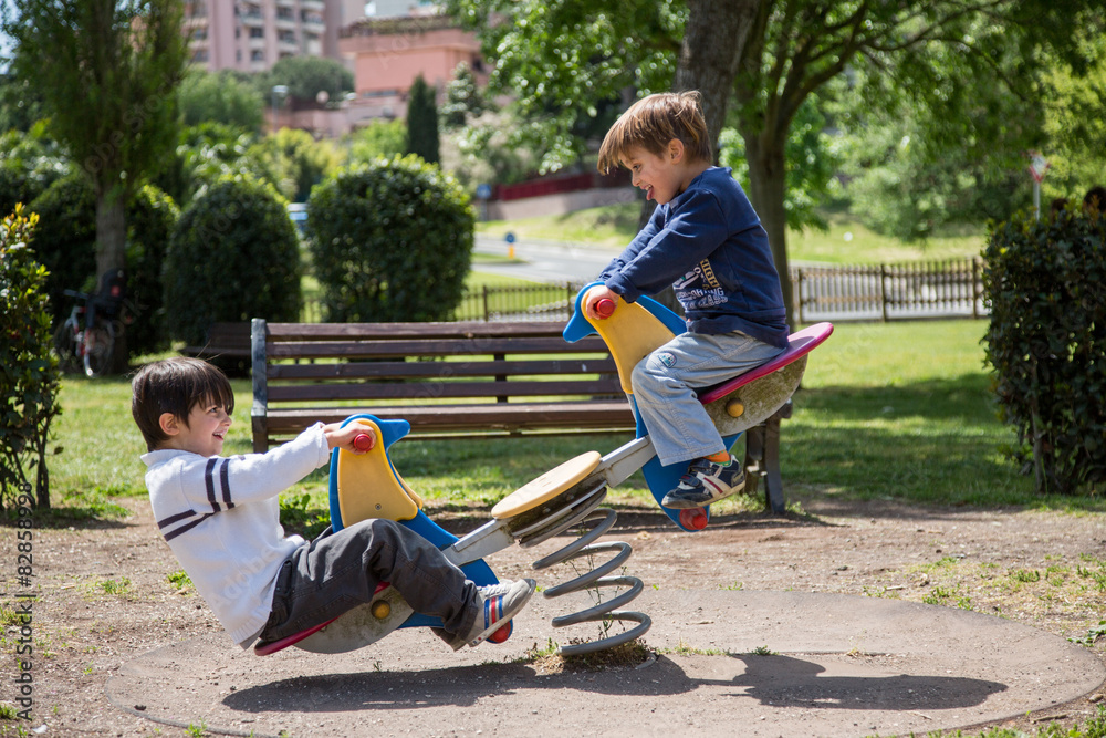 Foto Stock Coppia di bambini che giocano sul dondolo a molla | Adobe Stock