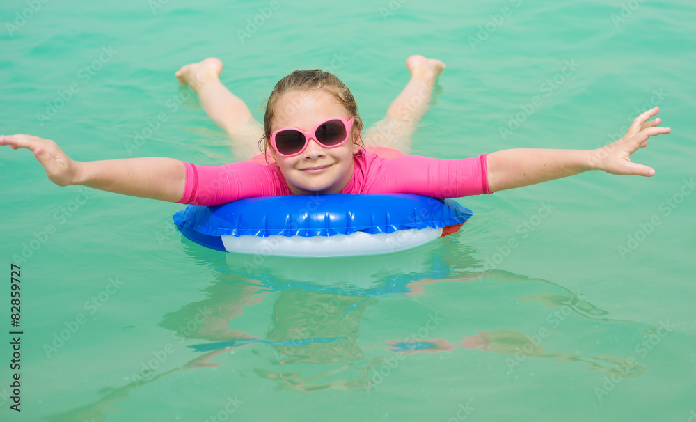 Smiling little girl with a floating ring at a tropical beach