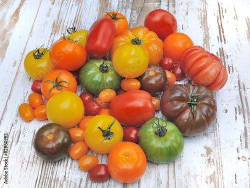 tomates de couleurs et de formes différentes sur fond bois blanc