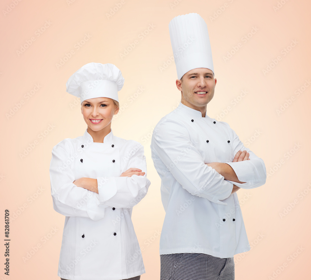 happy chefs or cooks couple over beige background