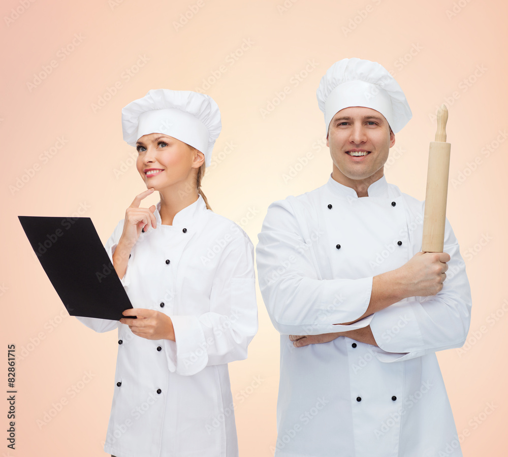 happy chefs or cooks couple holding rolling pin