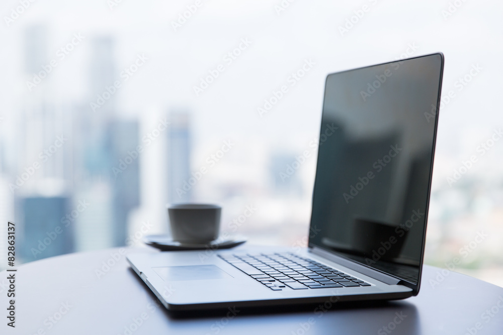 Fototapeta premium zamknąć laptopa i filiżankę kawy na stole w biurze