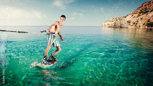 Wakeboarder rides a board on sea in. Wakeboarding on beach.