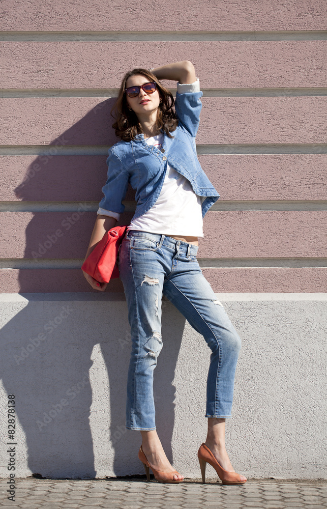 Beautiful woman body in denim jeans on wall background