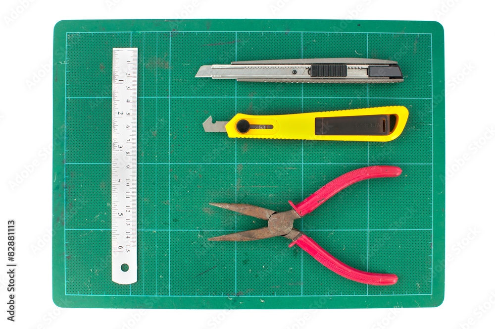 Fototapeta premium Green cutting mats with iron ruler pliers and cuter on white bac