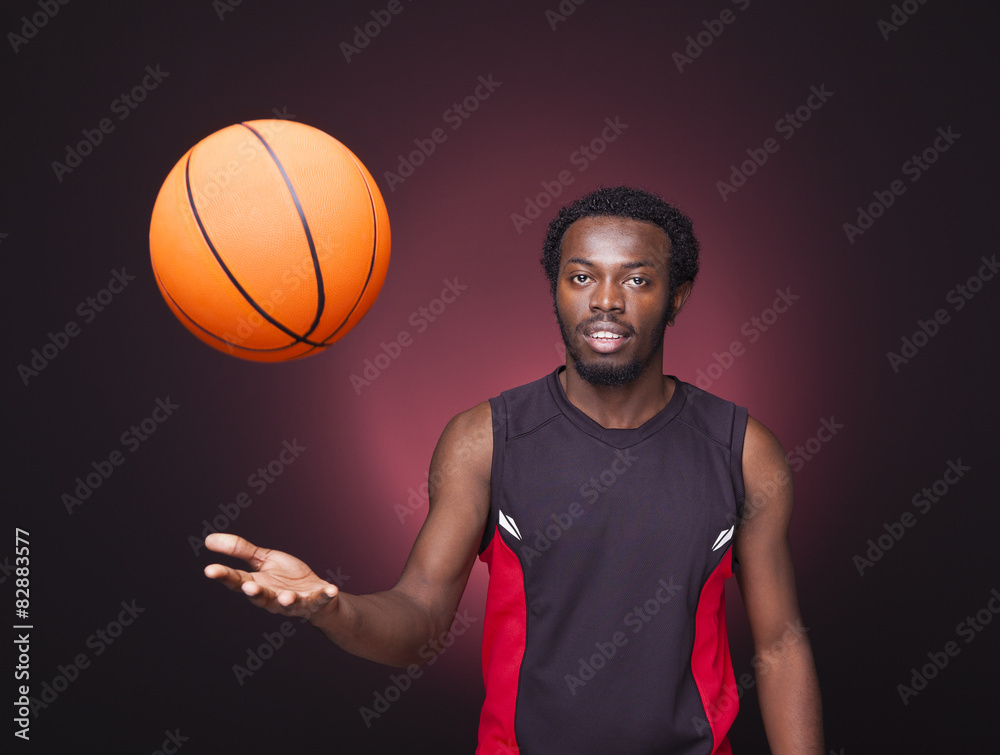 Basketball player playing with a basketball on dark background