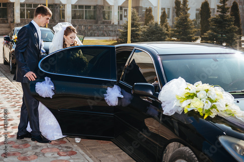 Fototapeta Bride and groom kissing in limousine on wedding-day.