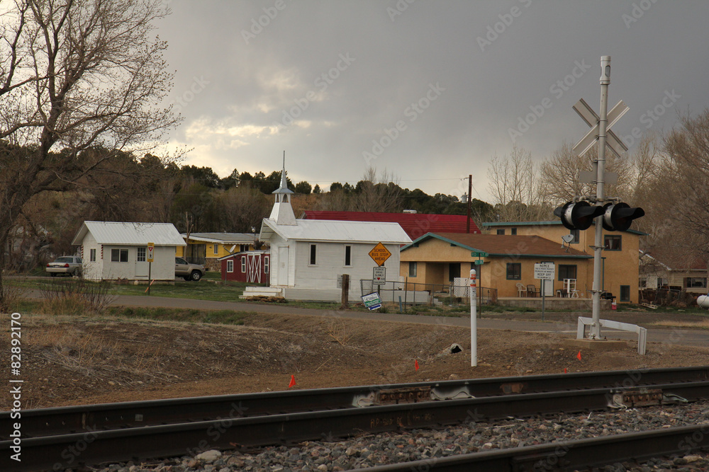 A small white church sits by the rail road tracks.