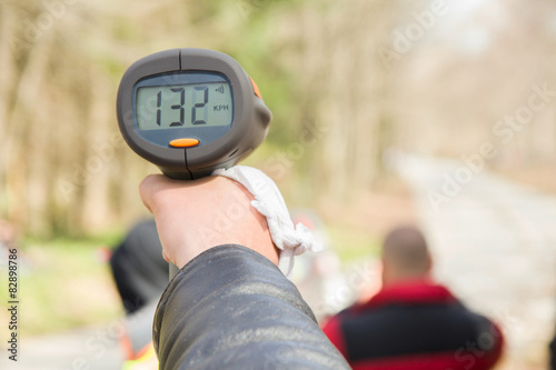 A police man hand pointing radar gun at speeding car
