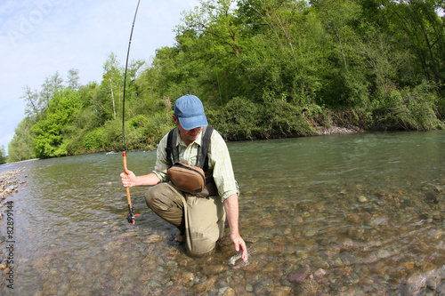 Fisherman catching brown trout with fishing line in river