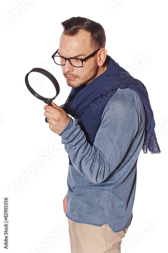 Serious man looking through magnifying glass