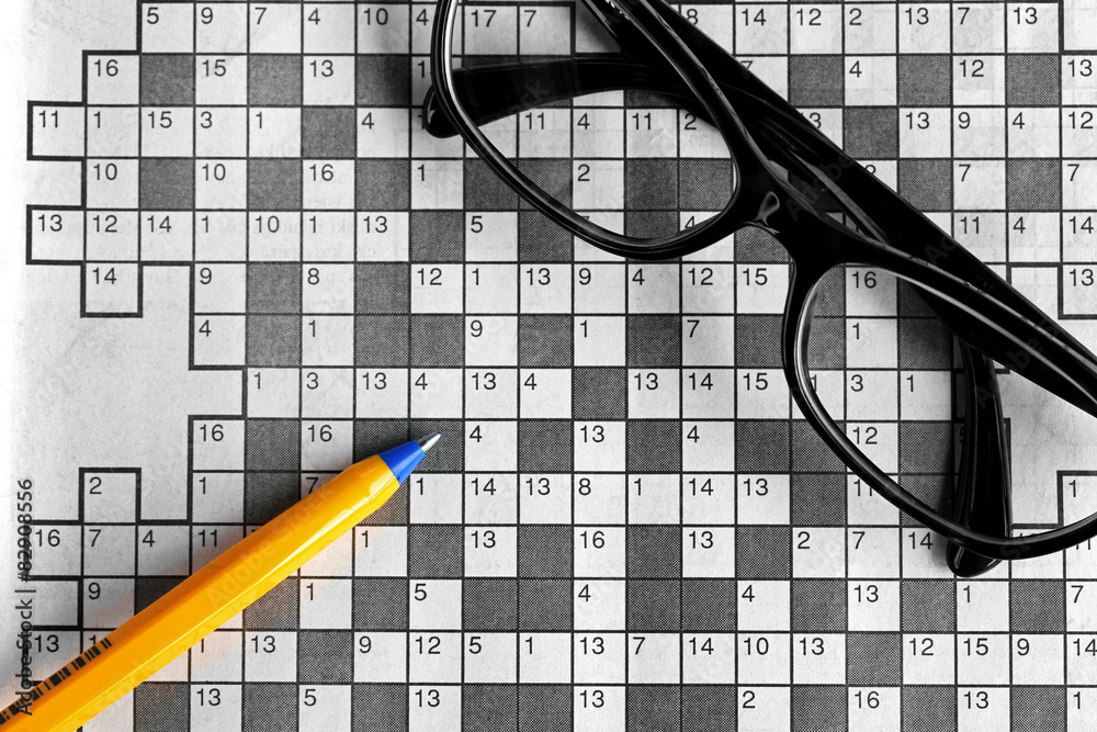 top view of blank crossword puzzle with black eyeglasses and a p Stock