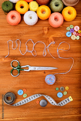 Word "make" with sewing tools on wooden background