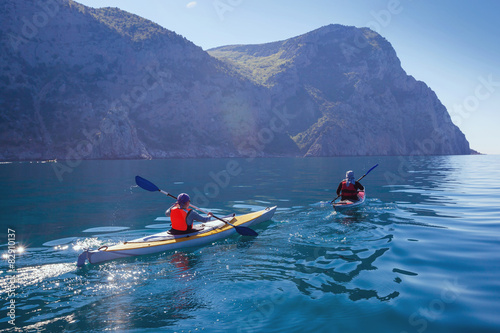 Kayak. People kayaking in the sea near the mountains.