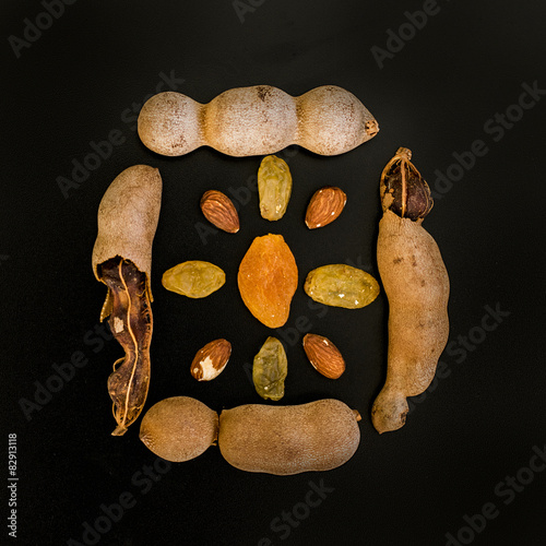 Tamarind, raisins and almond composition on black background