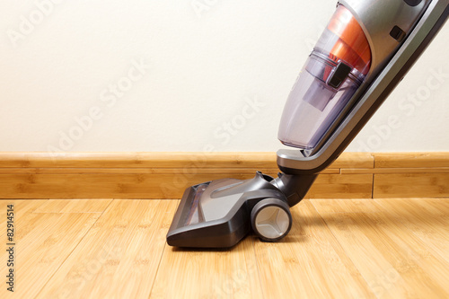 Cordless vertical vacuum cleaner cleaning parquet floor.