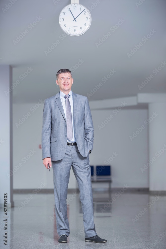 Business man in hall with clock on ceiling Business man in hall with clock on ceiling