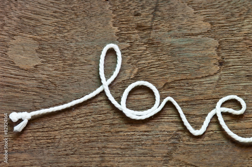 The word "love" written with rope on wood background