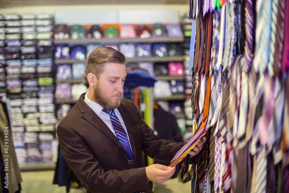 young man chooses a tie, costume shop young man chooses a tie, costume shop