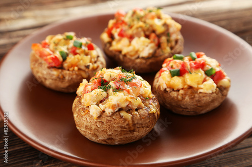 Stuffed mushrooms on plate on brown wooden background