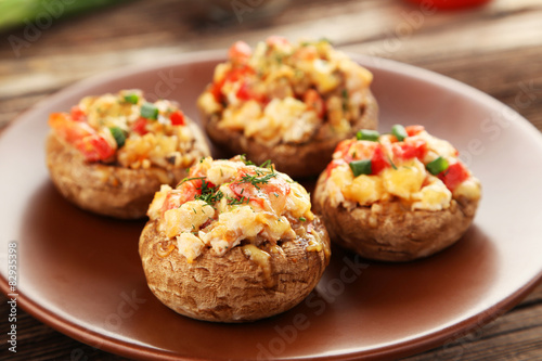Stuffed mushrooms on plate on brown wooden background