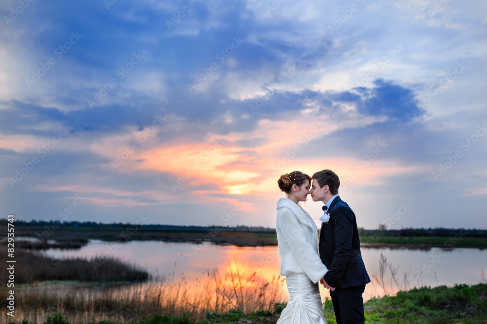 beautiful bride and groom hugging and looking at lake