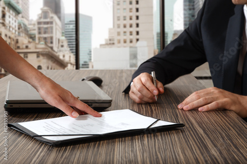 female hand pointing to businessman at signature place on a cont