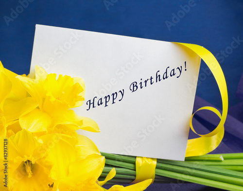 Bucket of narcissus flowers, envelope on blue-purple background