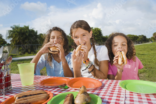 Hispanic girls eating at picnic table photo