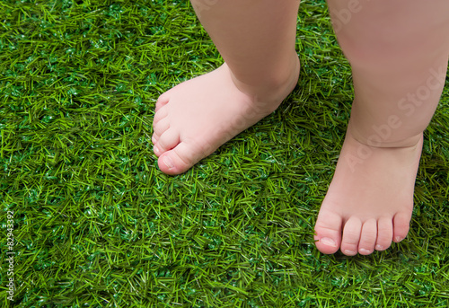 Baby bare legs standing on green grass