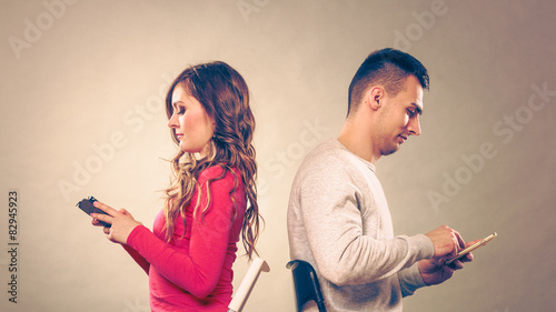 Couple using mobile phones not talking. Conflict. photo