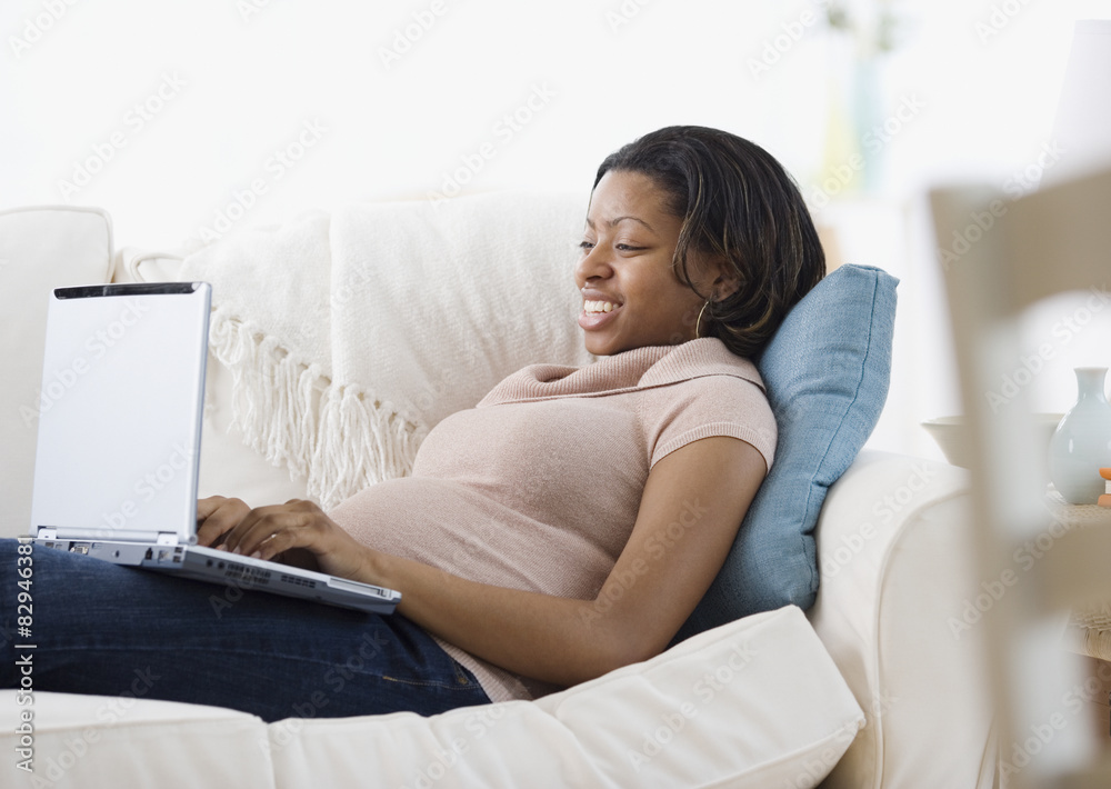 Pregnant African American woman typing on laptop Pregnant African American woman typing on laptop