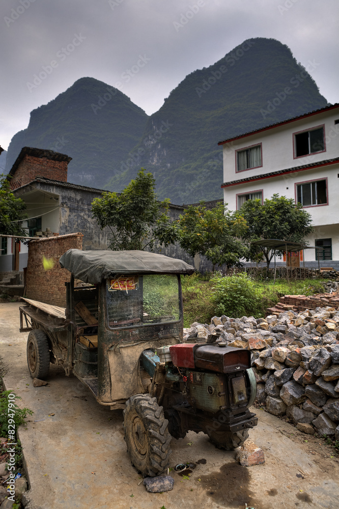 Battered ancient farmer tractor stands in peasant village 