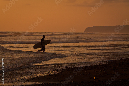 Silhouette of tourist surfer enjoying the sea during sunset