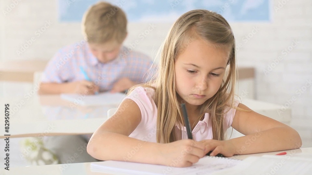 School girl writing on notebook in class School girl writing on notebook in class